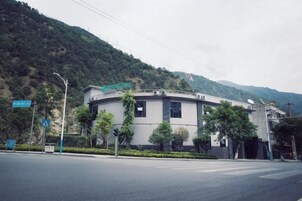 Un edificio con fachada curva, un letrero sobre la entrada y una calle delante con semáforo.