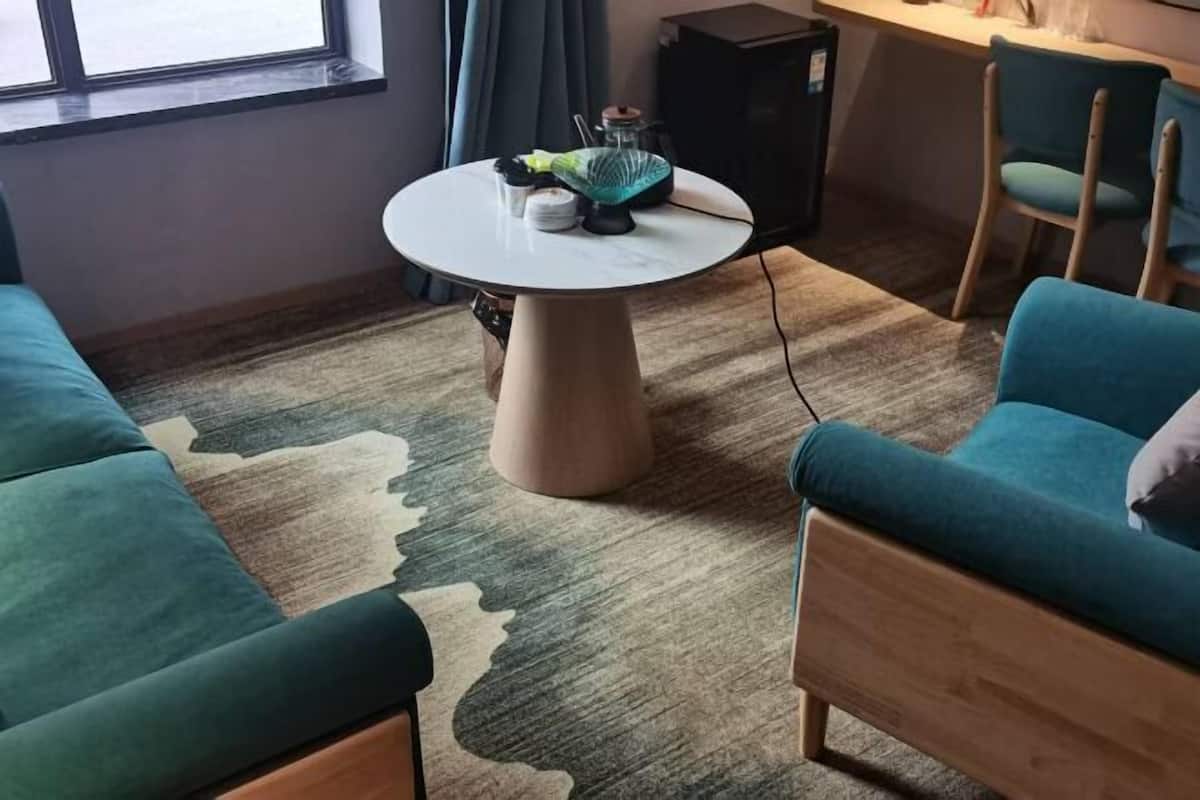 A modern living room with a round table, two sofas, and a small TV.