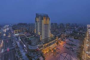 A high-rise building with multiple floors, surrounded by a parking area and other buildings.