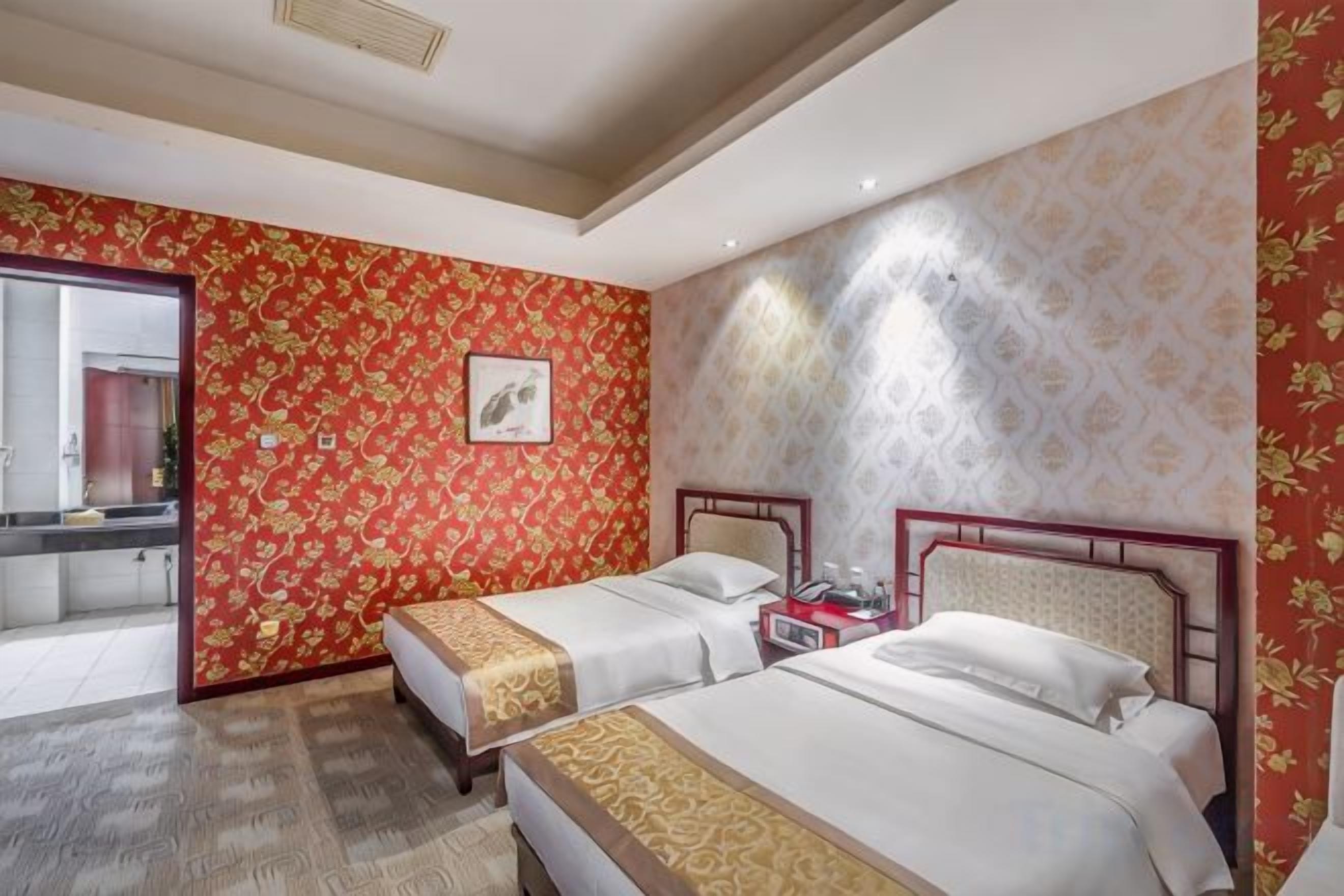 Een hotelkamer met twee bedden, een badkamer en uitzicht op buiten.