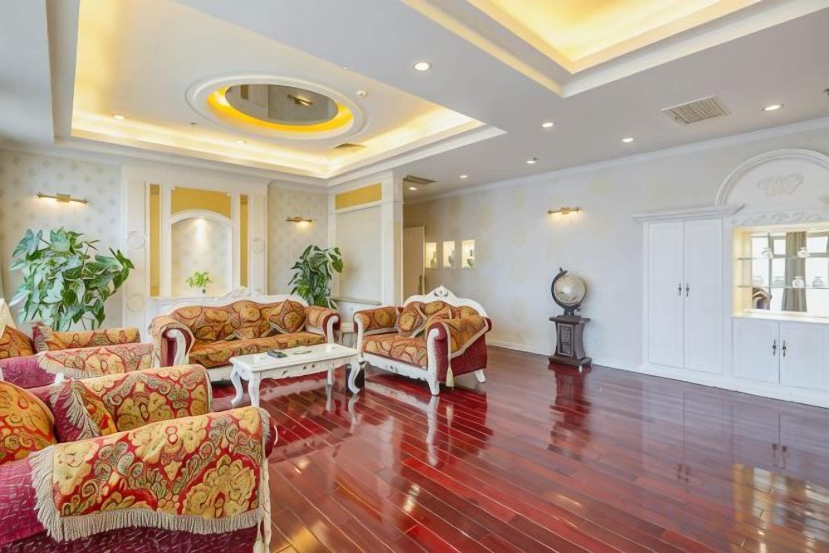 Een ruime woonkamer met een hoge plafond, versierde banken, een salontafel en een grote kast.