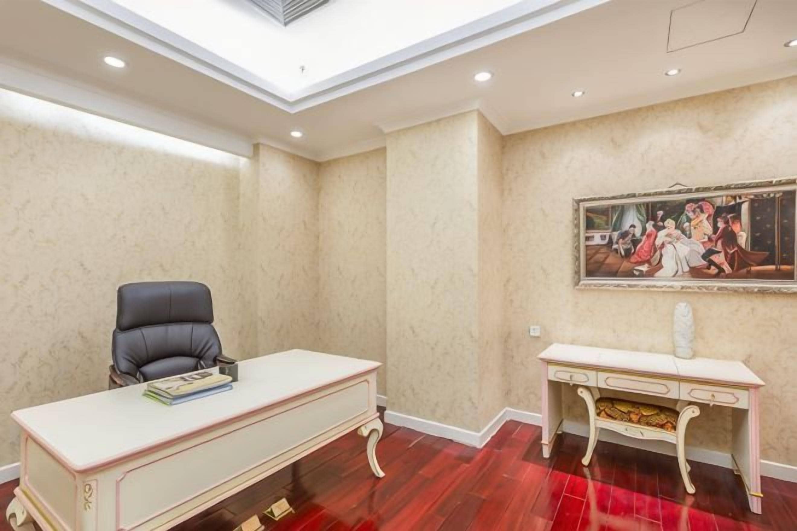 Een kamer met een bureau, een stoel, een console tafel en een schilderij aan de muur.