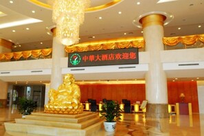 A hotel lobby with a large golden Buddha statue, a reception desk, and a sign indicating a hotel promotion. - Mei Di Ya Zhong Hua Hotel (Zhuolu)
