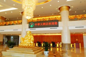 Un hall de hotel con una gran estatua dorada de Buda, un mostrador de recepción y un cartel que anuncia una promoción hotelera.