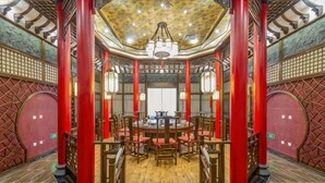 A traditional interior with a central round table, red pillars, and a patterned ceiling.
