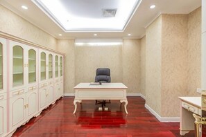 A conference room with a white desk, a black chair, and a cabinet with glass doors. - Mei Di Ya Zhong Hua Hotel (Zhuolu)