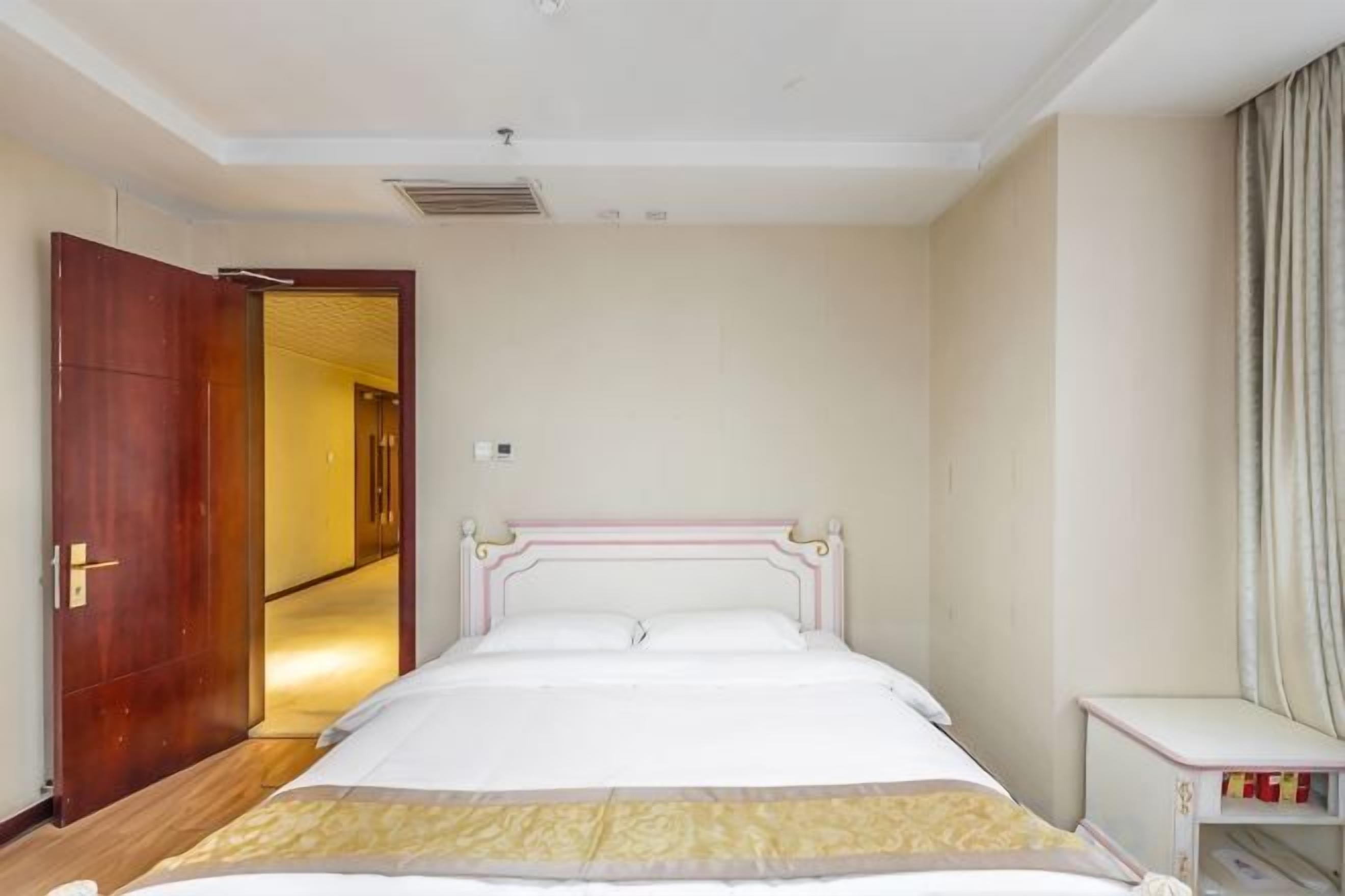 Une chambre d’hôtel comprenant un lit, une table de chevet, une armoire et une porte donnant sur une autre pièce.