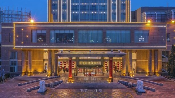 A modern hotel with a prominent entrance, large windows, and a well-lit facade.