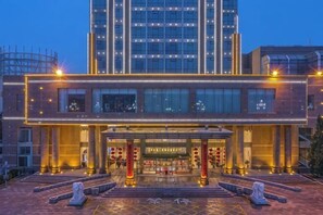 A modern hotel with a prominent entrance, large windows, and a well-lit facade. - Mei Di Ya Zhong Hua Hotel (Zhuolu)