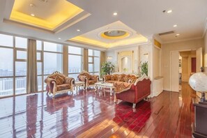 Un salon spacieux avec un plafond haut, de grandes fenêtres et une vue sur la ville.