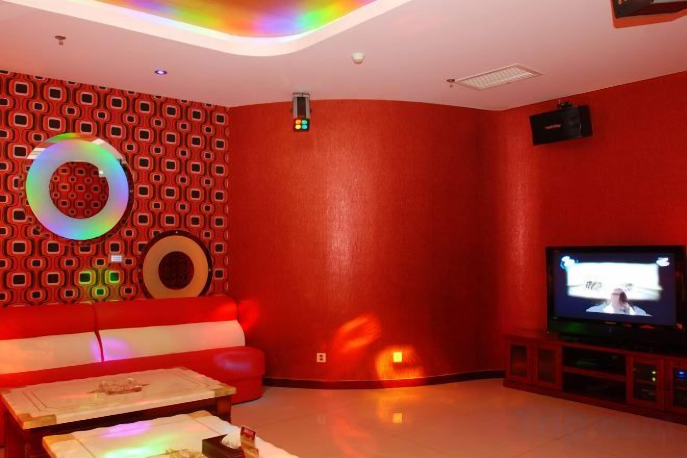 A red-walled room with a television, a circular light fixture, and a sofa.