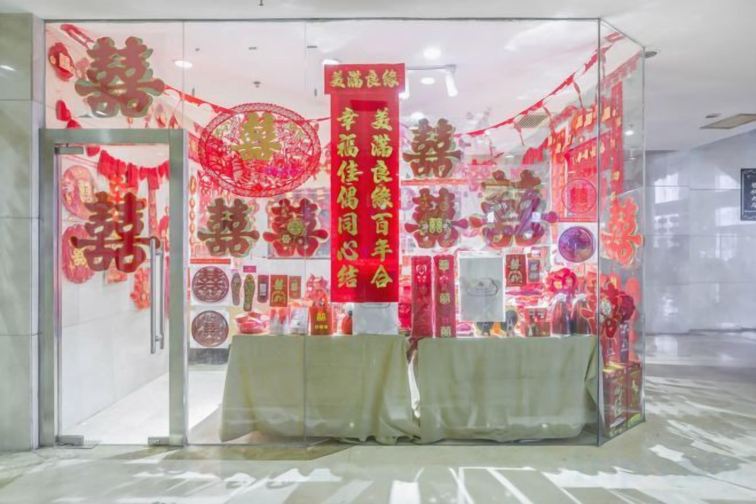 A room with a glass partition, a table with a tablecloth, and red decorations.