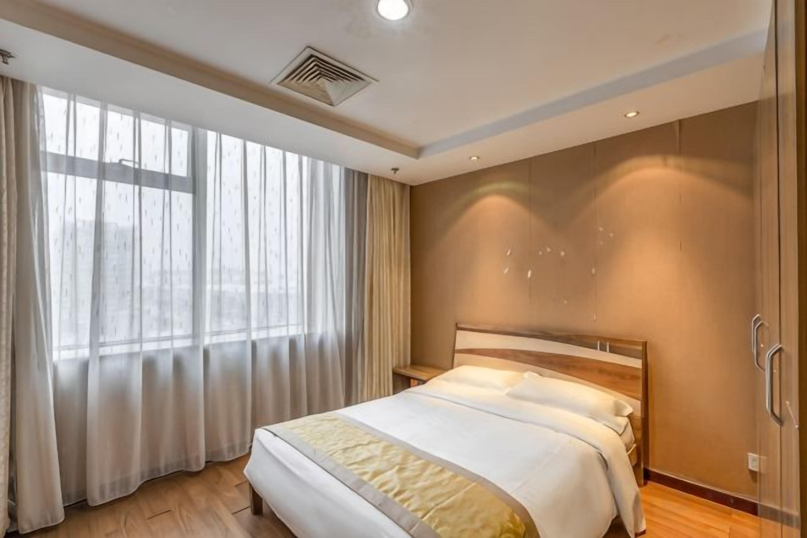 Habitació d'hotel amb un llit gran, una tauleta de nit i una finestra amb cortines.