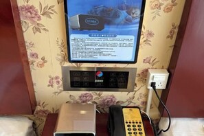 A hotel room with a floral wallpaper, a digital thermostat, a telephone, and a small electronic device on the nightstand. - Mei Di Ya Zhong Hua Hotel (Zhuolu)