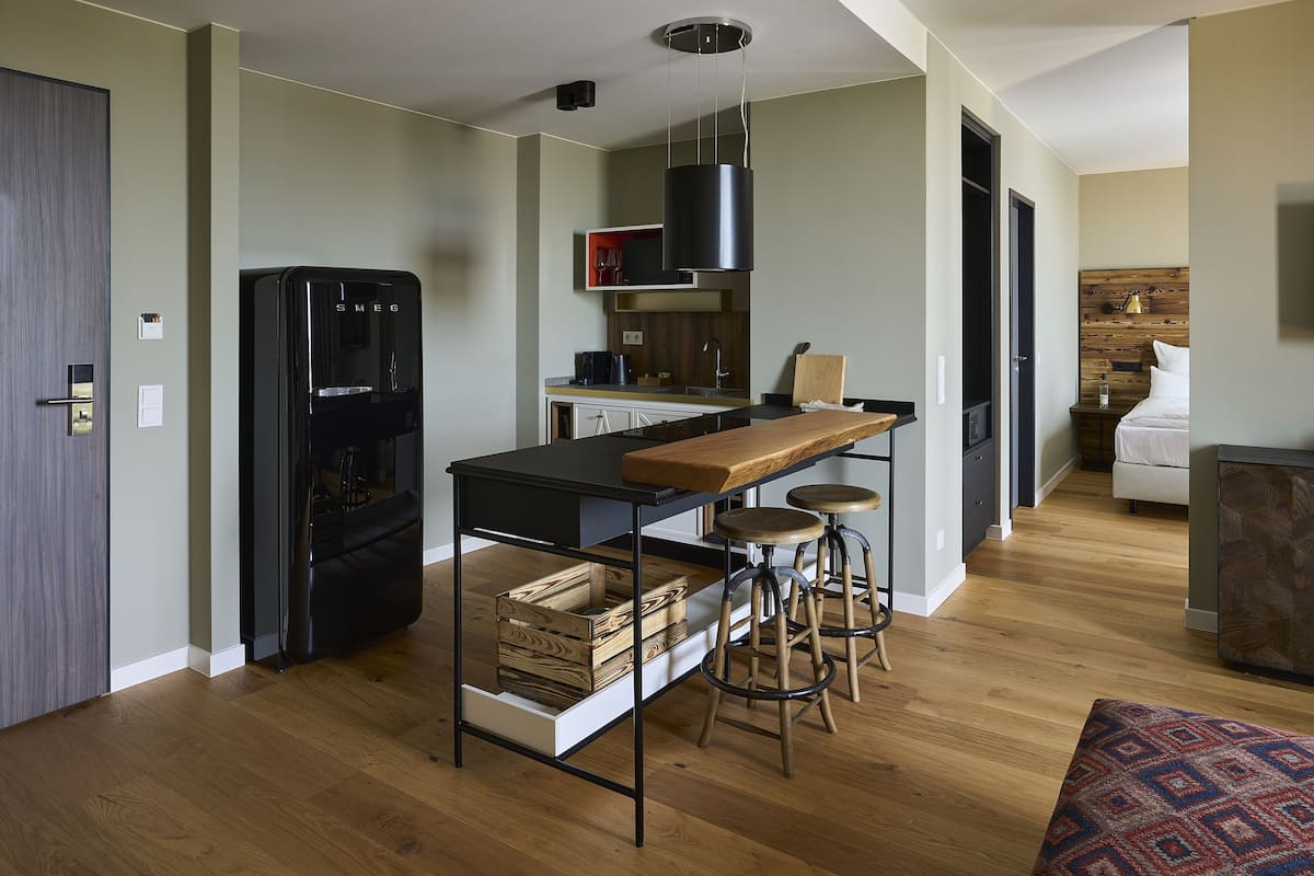 A modern kitchen with a black refrigerator, wooden stools, and a bar area.