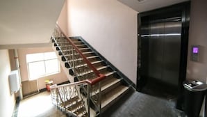 Una scala con ringhiera in metallo, un ascensore e un cestino.