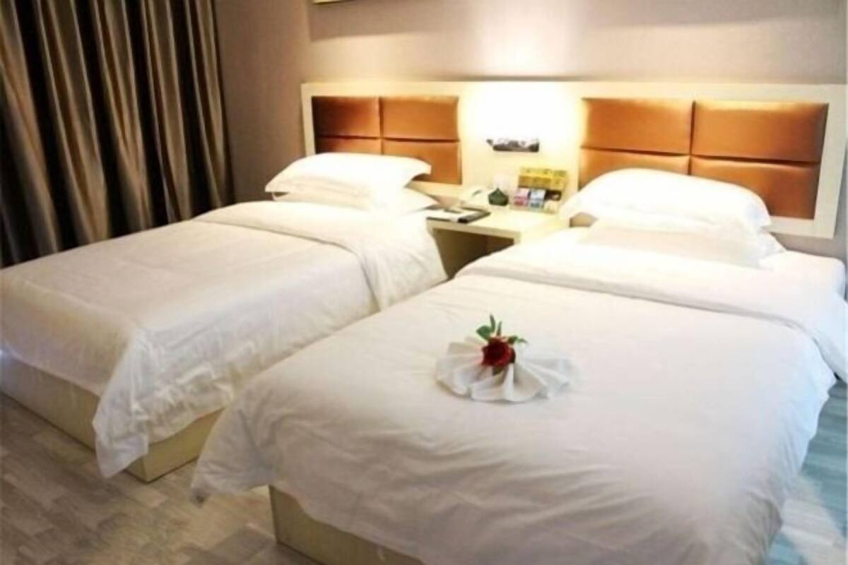 Una habitación de hotel con dos camas, cada una con cabecera y mesitas de noche.