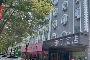 Un hotel con letrero, varias ventanas y un árbol en primer plano.