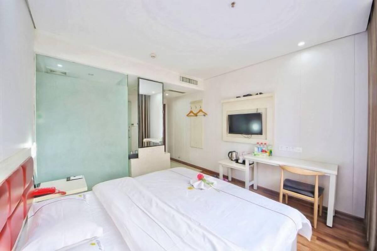 Una habitación de hotel con cama, escritorio, televisor y espejo.
