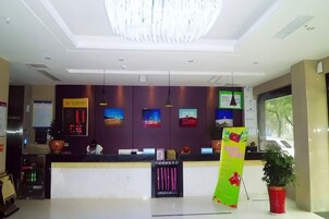 Un área de recepción de hotel con una lámpara araña moderna, un mostrador de recepción y un ventanal grande.