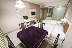 Una habitación de hotel con cama, escritorio, silla y una colcha morada.