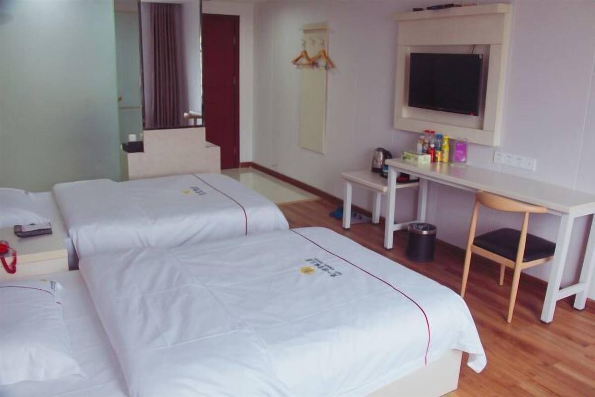 Habitación de hotel con dos camas, un escritorio, un televisor y una mesita con artículos de aseo.