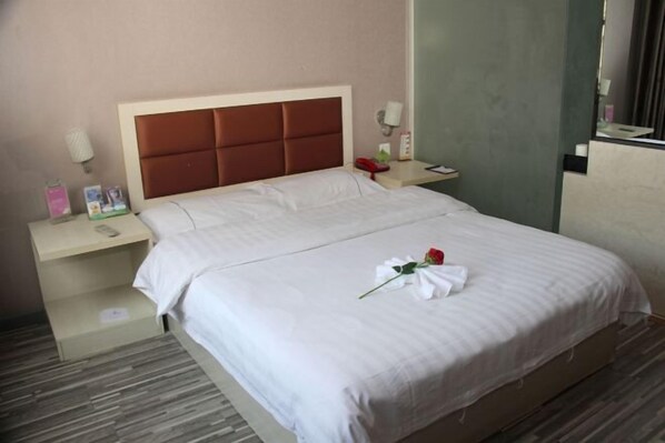 Habitación de hotel con cama, mesita de noche, espejo y teléfono fijo en la pared.