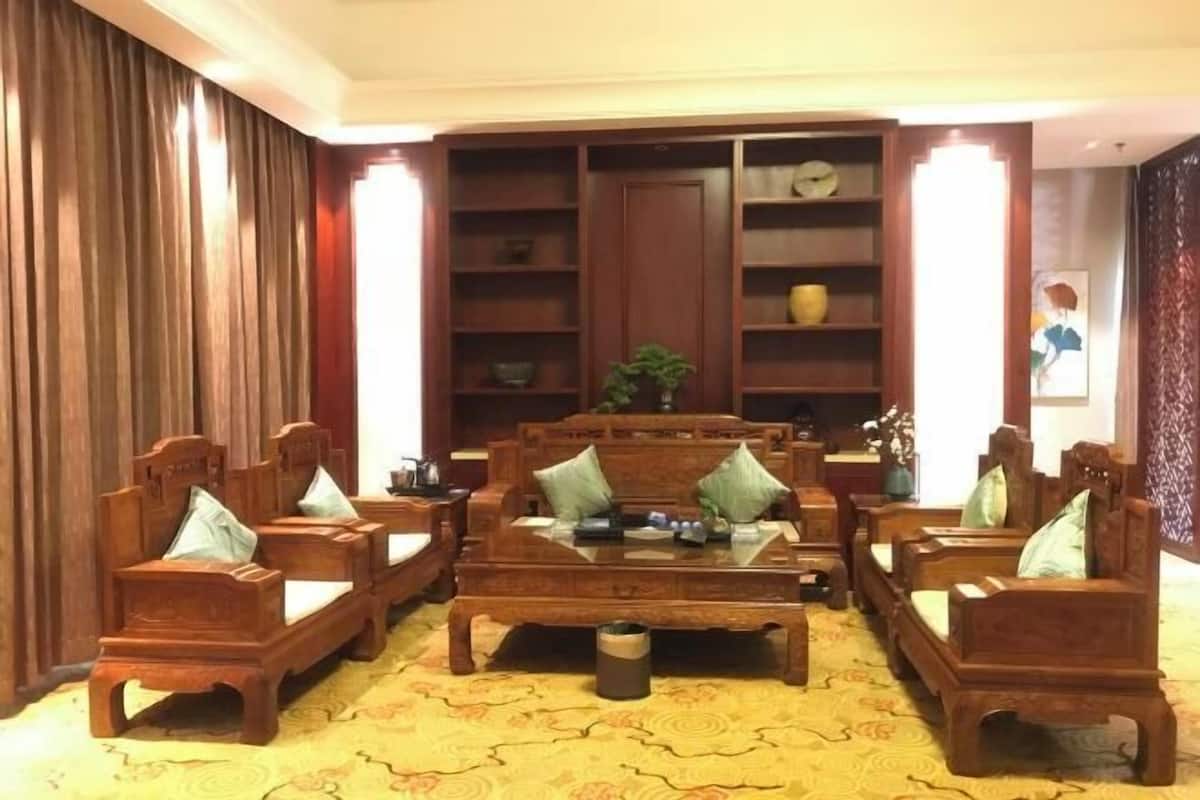 A traditional-style living room with wooden furniture, including sofas and a coffee table, and a bookshelf in the background.