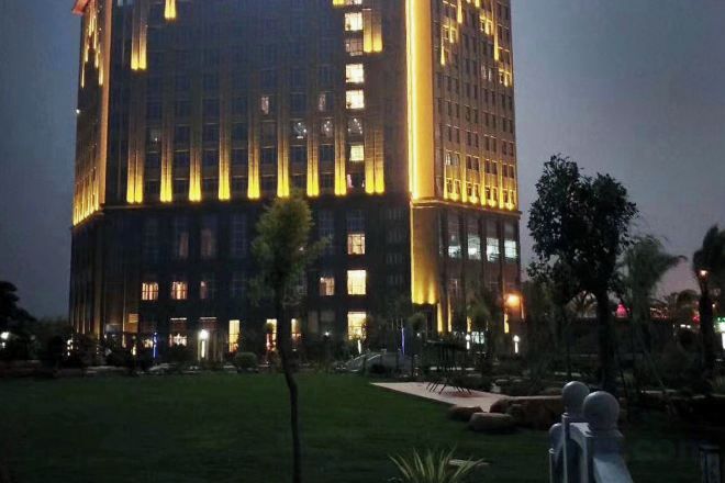 Un edificio alto con ventanas iluminadas y un césped cuidado en primer plano.