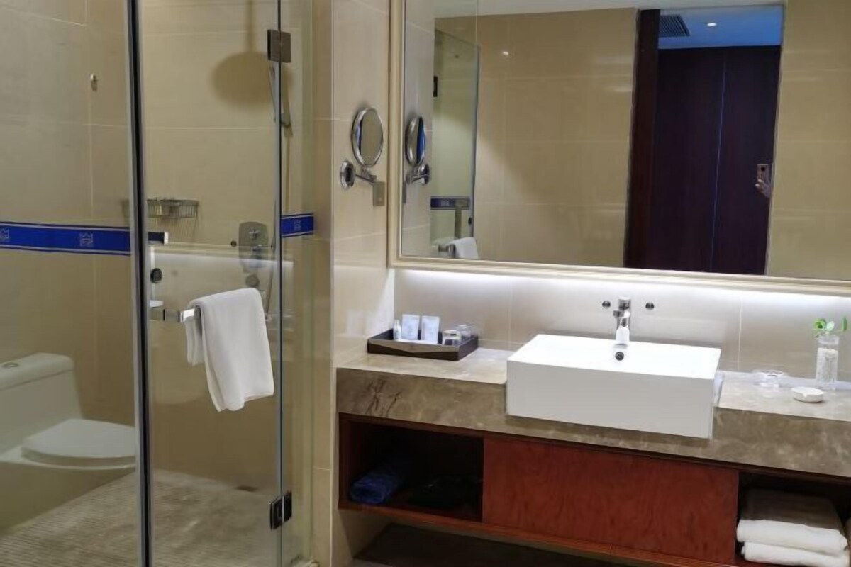 Un baño moderno con cabina de ducha de vidrio, un lavabo blanco y un espejo grande.