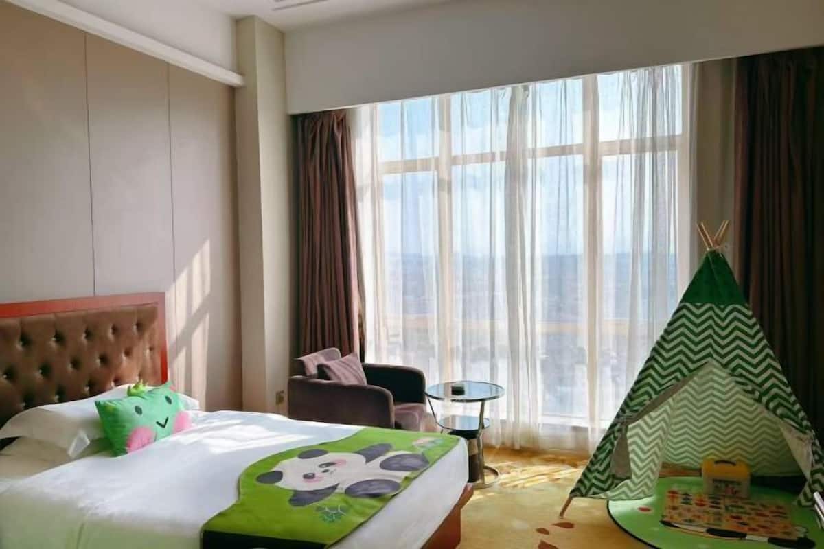 A hotel room with a bed, a chair, a small table, and a teepee.