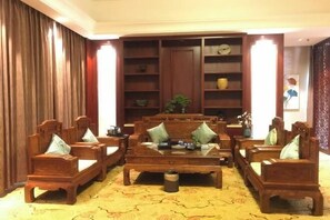 Una habitación tradicional con muebles de madera, incluyendo sofás y una mesita de centro, y una estantería.