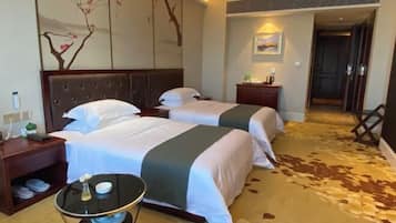 A hotel room with two beds, a nightstand, a small table, and a decorative wall piece.