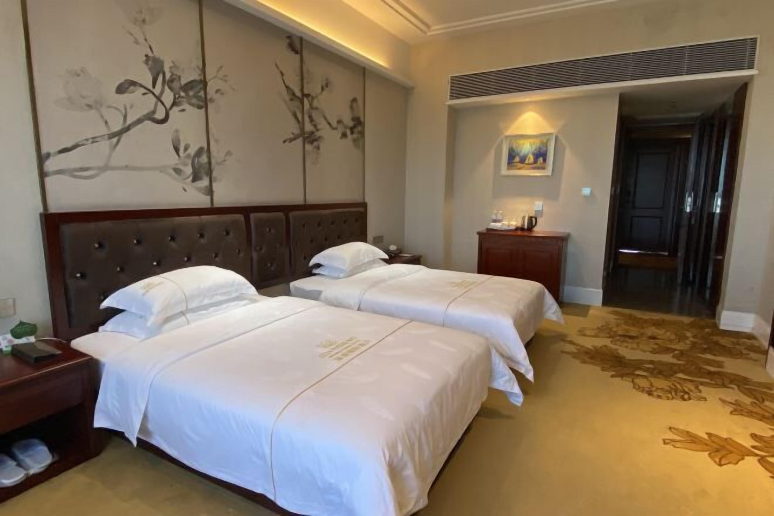 A hotel room with two beds, a nightstand, a dresser, and a painting on the wall.