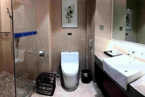 Un baño moderno con cabina de ducha de vidrio, inodoro, lavabo y cubo de basura.