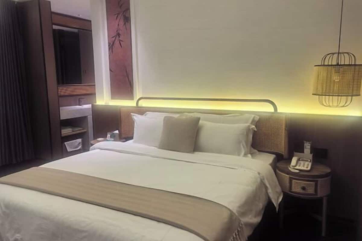 A hotel room with a bed, bedside table, lamp, and a wardrobe.