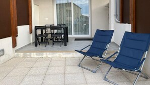 A balcony with a table and chairs, a sliding glass door, and a view of a house.