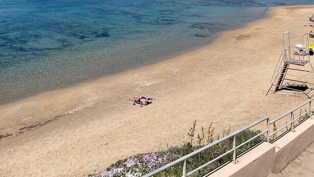 A beach with clear blue water, a sandy shore, and a lifeguard tower.