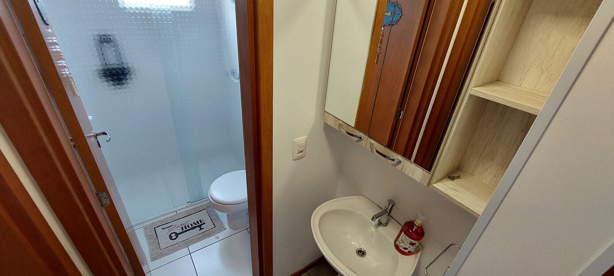 A small bathroom with a toilet, sink, and a mirror above the sink.