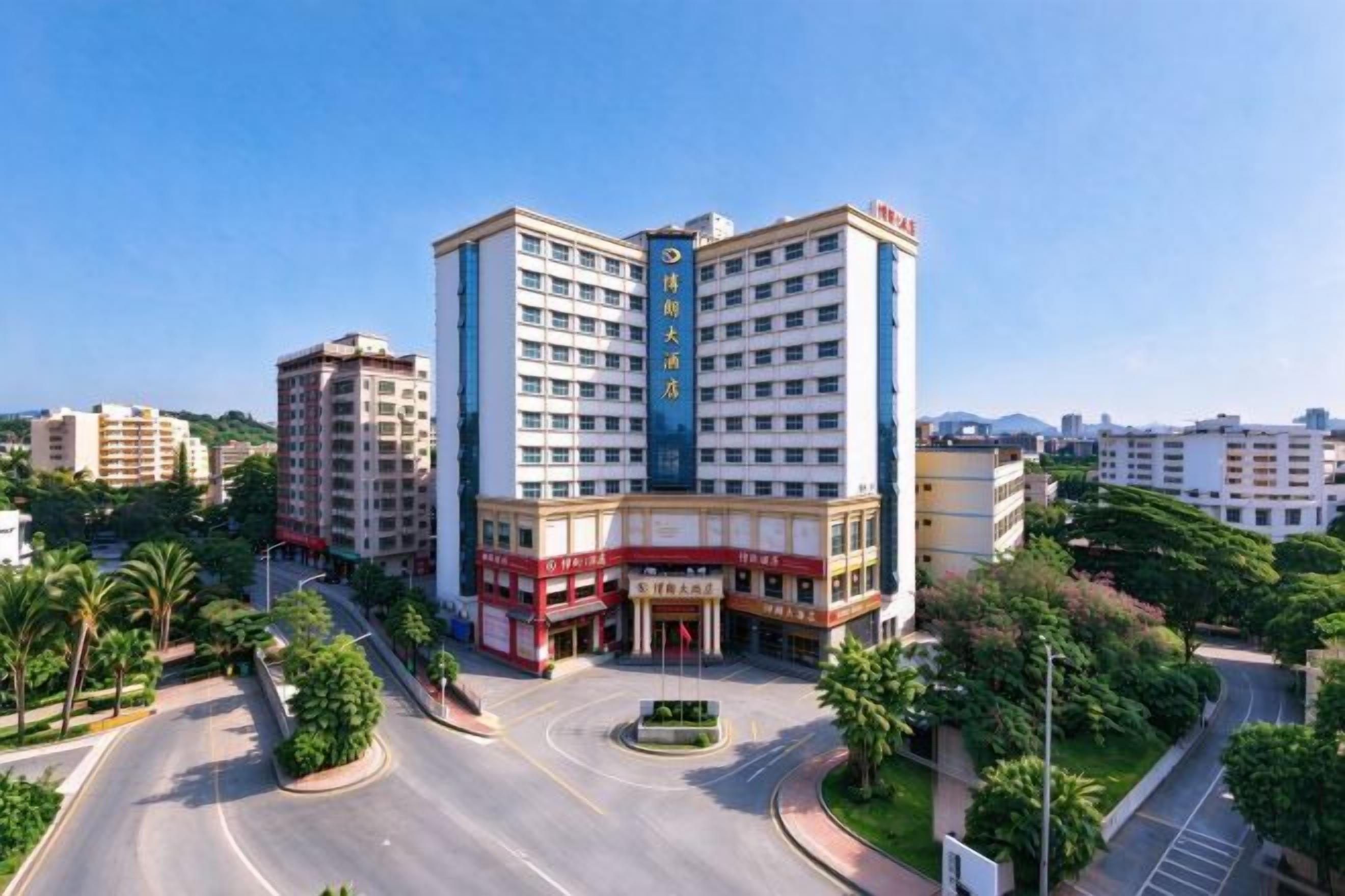 Un hotel a più piani con un cortile centrale, circondato da vegetazione e una rotatoria.