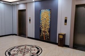 A hallway with elevators, a decorative wall, and a patterned floor. - Shenzhen Bolang Hotel (Xintangwei Metro Station) (Shenzhen)
