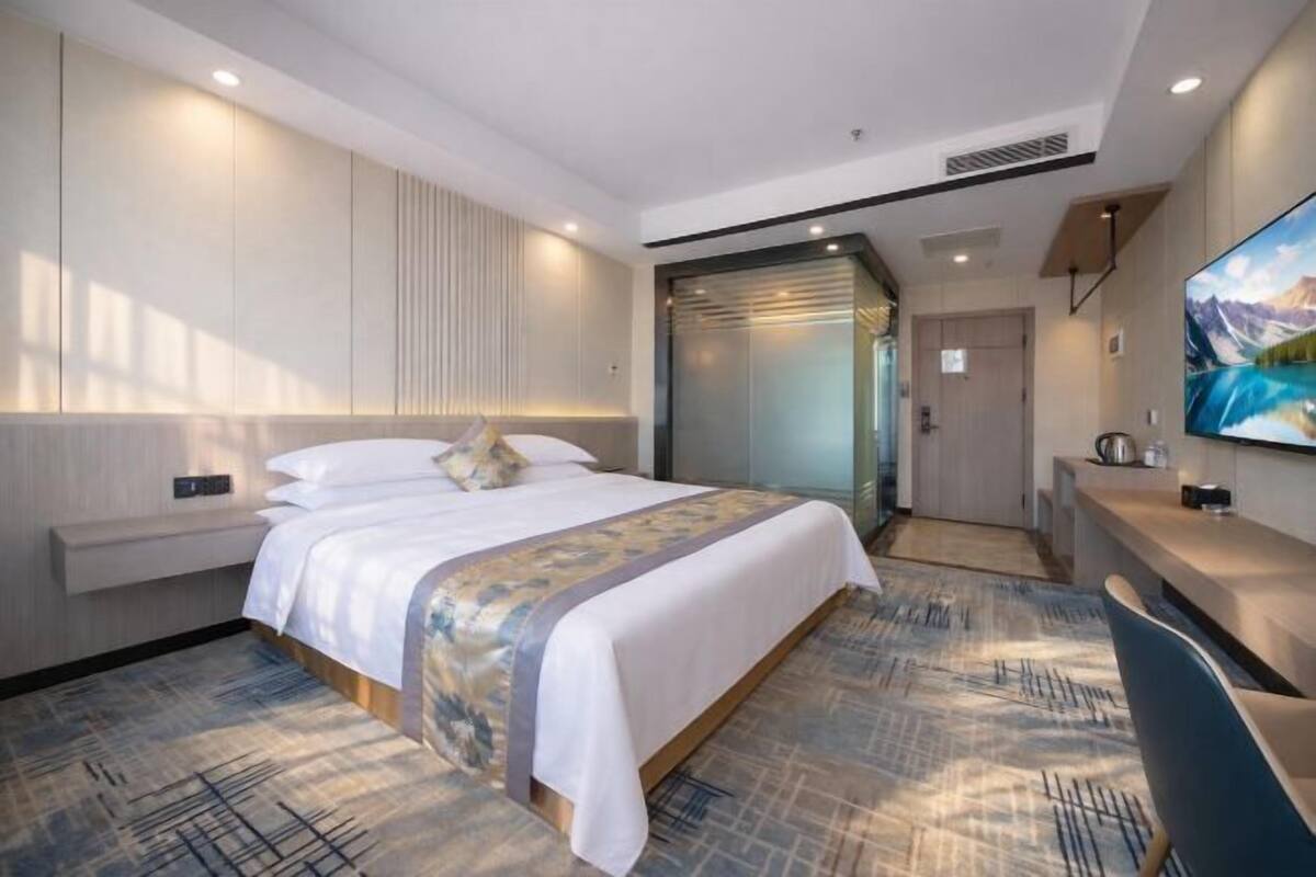 A modern hotel room with a large bed, a desk, and a TV.