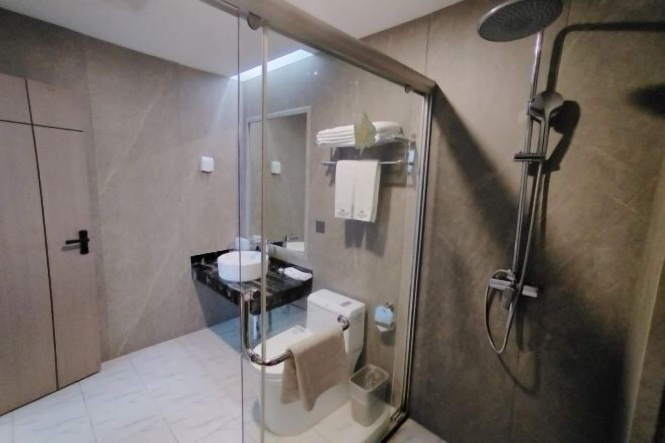 Uma casa de banho moderna com cabine de chuveiro em vidro, sanita e lavatório.