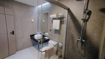 Uma casa de banho moderna com cabine de chuveiro em vidro, sanita e lavatório.