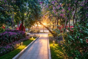 A pathway leading to a seating area with tables and chairs, surrounded by lush greenery and flowering plants. - Shenzhen Bolang Hotel (Xintangwei Metro Station) (Shenzhen)