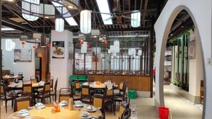 A restaurant with round tables and chairs, a wooden ceiling, and a decorative wall with a window. - Shenzhen Bolang Hotel (Xintangwei Metro Station) (Shenzhen)