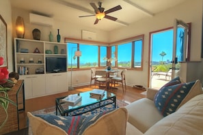 A spacious living room with a large window, a ceiling fan, and a dining area with a view.