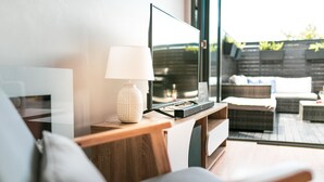 Un salon moderne avec un téléviseur à écran plat, une lampe et un canapé.