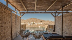 A terrace with a pool, wooden walls, and a view of a mountain and lake.
