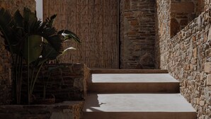A stone staircase leading to a wooden door, surrounded by stone walls and a potted plant.
